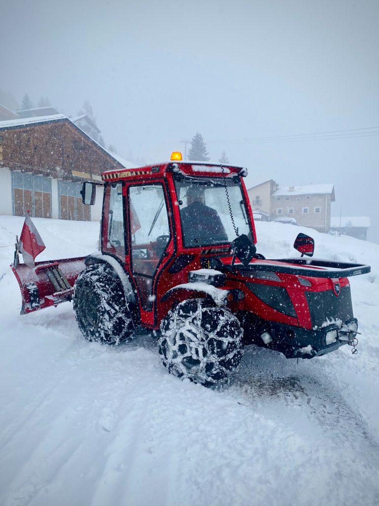 red and black tractor on snow covered ground during daytime